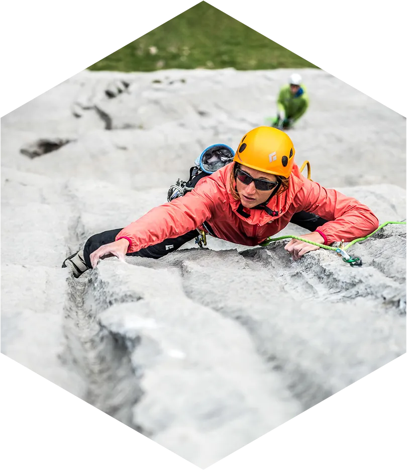 entretien de matériel d'escalade, femme équipée vue de haut en train d'escalader une paroi de pierre
